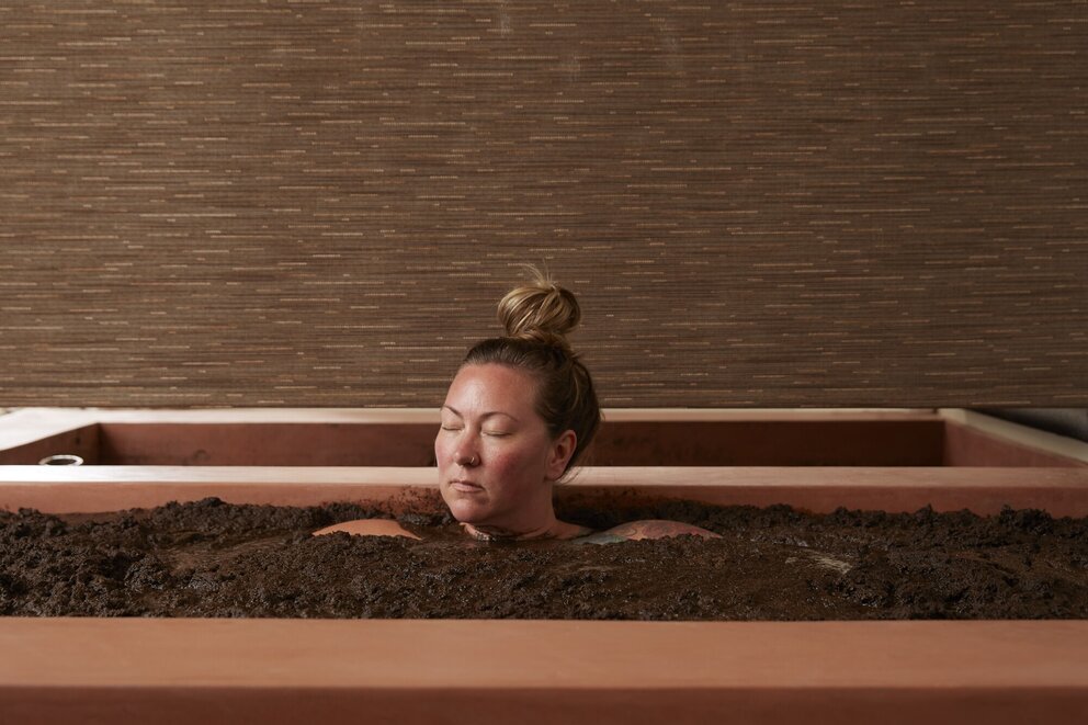 person sitting in mud bath
